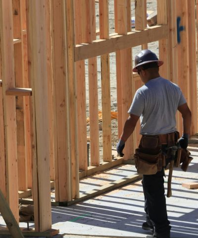 Construction worker on site building wooden frame home during the day.