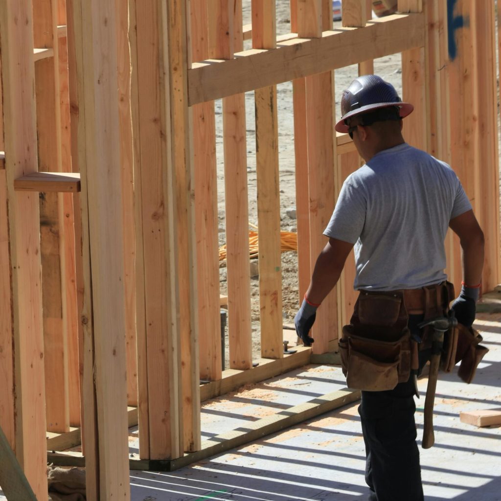 Construction worker on site building wooden frame home during the day.